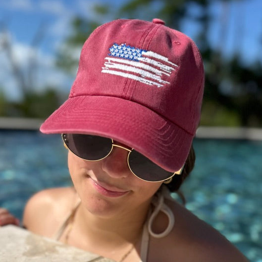 Person wearing a red cap with an American flag embroidered by a pool