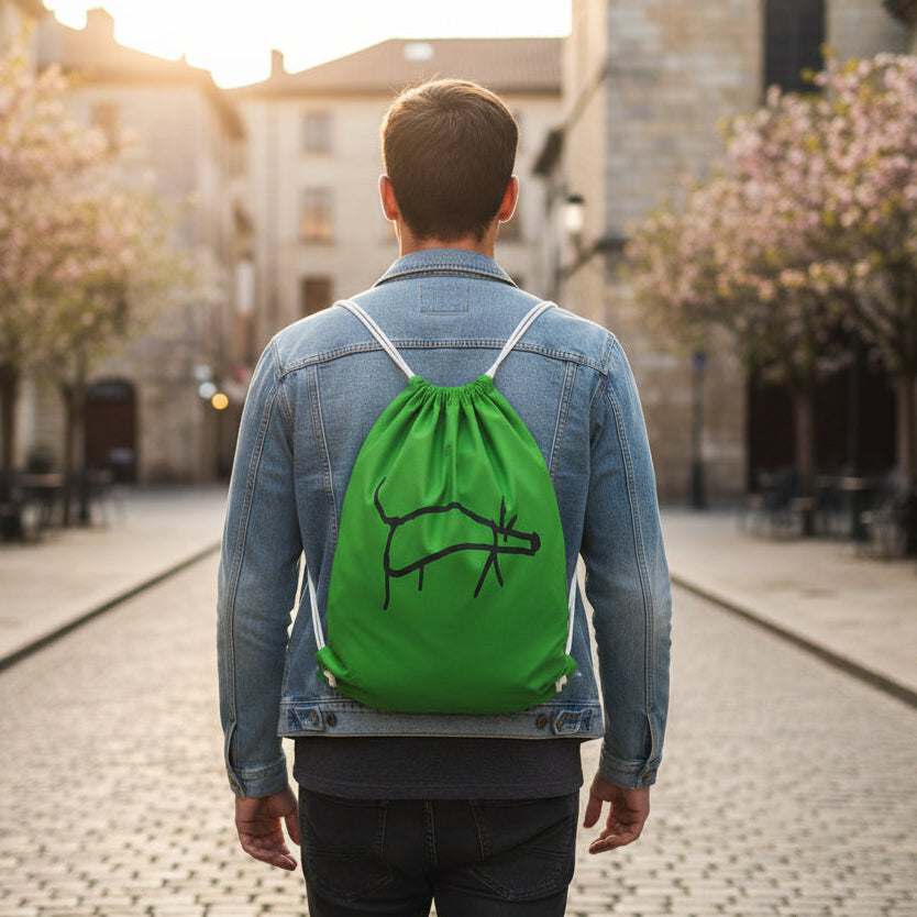 Person wearing a green drawstring bag with a black design on a street.